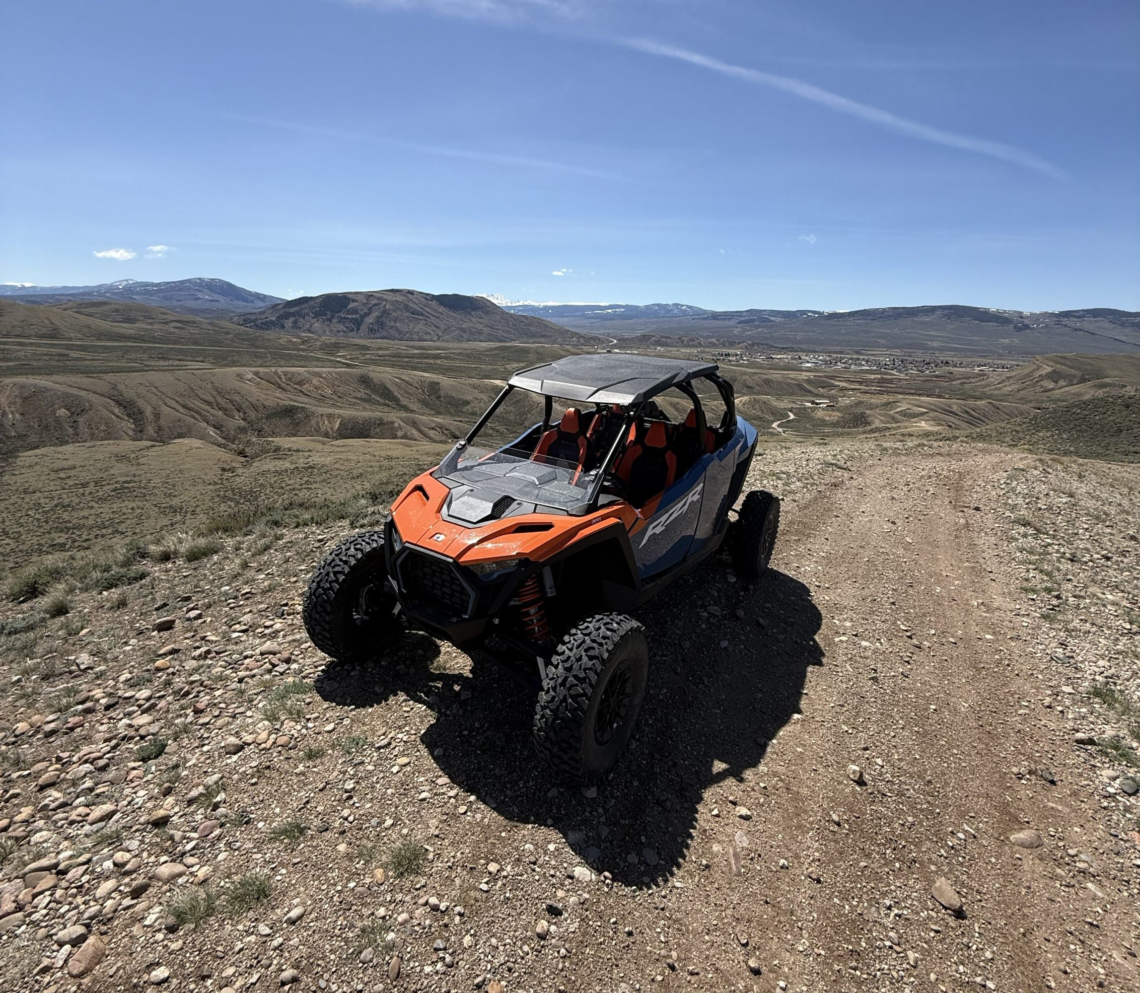 Off-road vehicle on a rocky trail with a vast mountain landscape in the background.